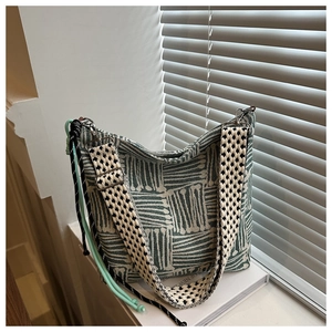 Dettaglio della borsa tote in tela jacquard verde con tracolla a pois e corde decorative