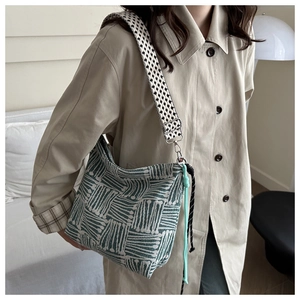 Detail of green striped crossbody bag with wide houndstooth shoulder strap and soft texture