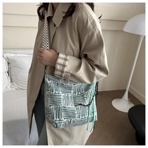 Dettaglio borsa tote intrecciata verde e bianca con tracolla a scacchi e coulisse laterale