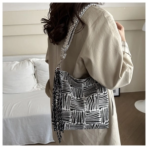 Dettaglio della grande borsa tote in tweed bianco e nero con eleganti frange lunghe laterali