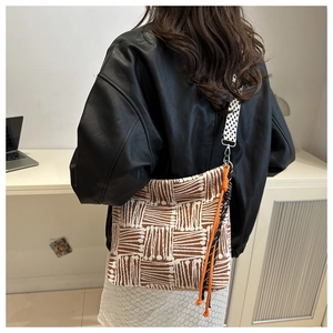 Detailed side view of large geometric jacquard tote bag with wide woven strap and orange drawstring