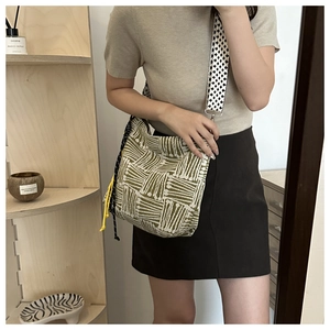 Dettaglio borsa in tela intrecciata verde e beige con coulisse gialla e tracolla pied-de-poule