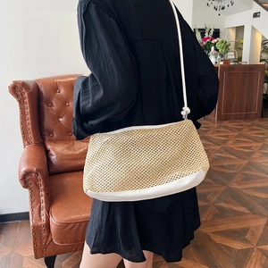 Straw weave crossbody bag with white leather trim shown in a stylish indoor setting