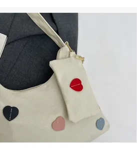Detail of canvas tote bag with colorful heart patches and detachable small coin purse