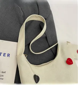 Detail of canvas tote bag featuring heart patches on a textured fabric background