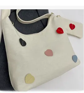Detail of white canvas tote bag with multi-color heart patches and matching small pouch