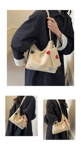 Detail of off-white canvas tote bag with colorful heart patches and a mini coin purse