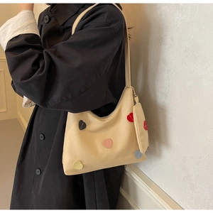 Detail of canvas tote bag with multi-colored heart patches and mini coin purse charm