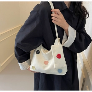 Canvas tote bag detail showing colorful heart patches and a mini zipper coin pouch