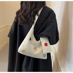 Detail of canvas tote bag with multi-color heart patches and matching heart-shaped pouch