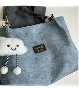 Close-up of blue canvas tote with plush cloud charm and black leather straps