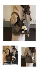 Detail of dark grey tote bag with cloud plush charm and brand label on matte leather