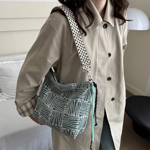 Green and white woven tote bag with a wide houndstooth shoulder strap and rope detail
