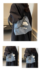 Detail of blue canvas tote bag with black leather straps and cloud plush charm
