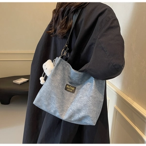 Minimalist washed blue canvas tote bag with black leather straps and plush heart charm