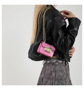 Détail d'un mini sac rose avec bandoulière chaîne dorée porté par un mannequin