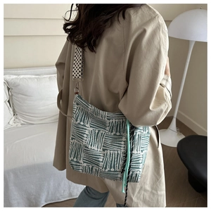 Detail of green and white patterned tote bag with wide geometric strap on model