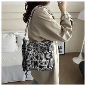 Detail of geometric woven tote bag with wide strap and decorative tassel accents