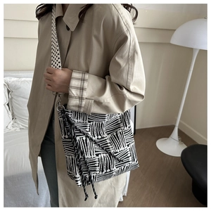 Detailed side view of black and white striped canvas tote bag with woven knot strap