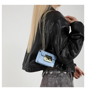 Détail d'un mini sac bleu clair avec fermoir doré et bandoulière en chaîne élégante