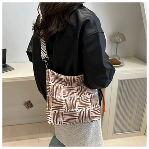 Detail of checkered shoulder strap and jacquard textured tote bag on a model