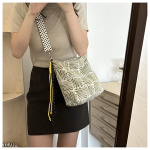 Close-up of canvas crossbody bag with green geometric patterns and star print strap