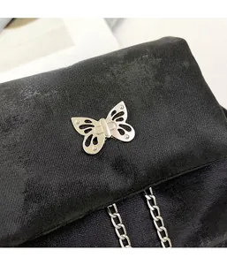 Detail of silver butterfly metal clasp with chain on black twill fabric backpack