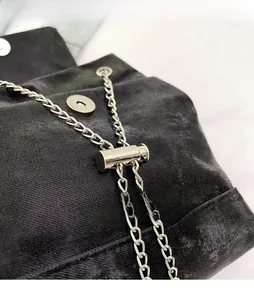 Detail of silver chain drawstring and magnetic buckle on black fabric mini backpack