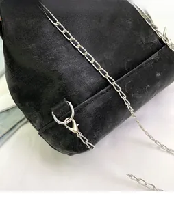 Close-up of black washed canvas backpack showing silver metal chain strap and ring detail