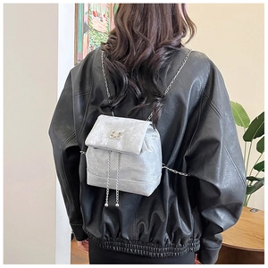 Detail of silver velvet mini backpack featuring a metallic butterfly and chain strap