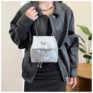 Macro shot of silver velvet mini backpack featuring a metallic butterfly clasp and chain
