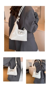 Detail of white glossy shoulder bag with silver bow accent and knotted strap texture