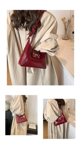 Detail of dark red glossy shoulder bag with silver bow and knotted strap design