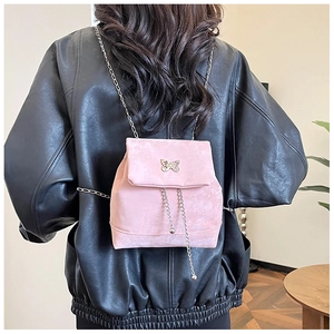 Detail of pink suede mini backpack with gold butterfly buckle and metal chain straps