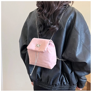 Macro detail of a mini pink bow backpack featuring a metallic butterfly and chain
