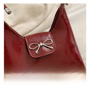Close-up of wine red patent leather handbag featuring a silver bow-shaped metal buckle