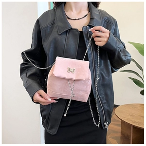 Detailed macro view of pink suede mini flap bag with golden butterfly and silver chain