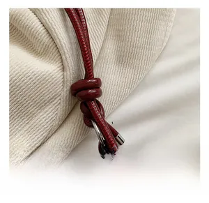 Detail of red leather cylindrical strap with adjustable knot and silver metal hardware