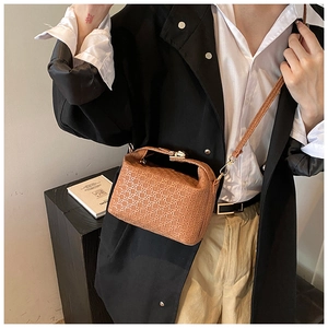 Detail of a brown woven texture shoulder bag featuring gold buckle and leather strap