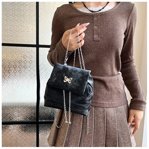 Detail of black velvet mini backpack with silver metal bow clasp and chain strap