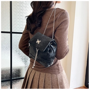 Close-up of black retro textured backpack with silver bow buckle and chain strap detail