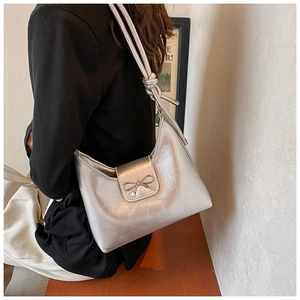Silberne Schultertasche Detail mit Schleifendekoration und Faltenstruktur auf Glattleder