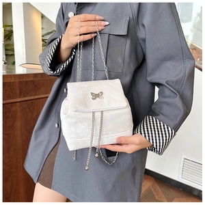 Close-up of white mini backpack with a metallic butterfly clasp and fine silver chain straps