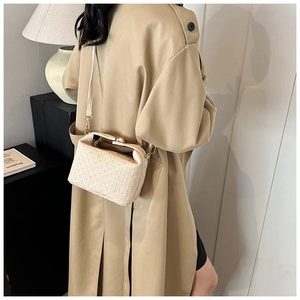 Detail of a beige woven leather handbag with retro metal clasp on a khaki coat