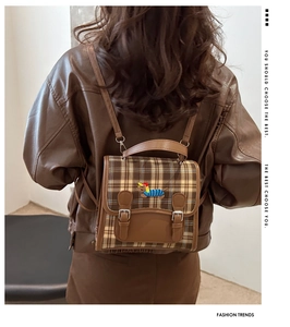 Detail of retro plaid backpack featuring embroidered puppy and silver buckle on model