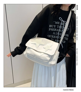 Close-up of white canvas shoulder bag featuring plush star patches and side pockets