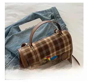 Detail of vintage plaid handbag featuring cute caterpillar embroidery and leather handle