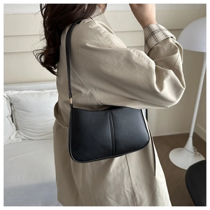 Sac hobo noir en cuir avec doubles surpiq surpiqûres verticales porté à l'épaule par un mannequin