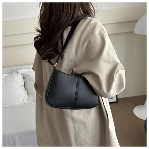 Minimalist black leather underarm bag with sleek stitching and gold metal hardware detail