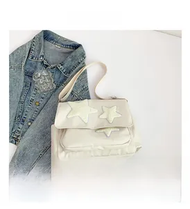 Detailed close-up of cream canvas crossbody bag featuring three embroidered stars on the flap